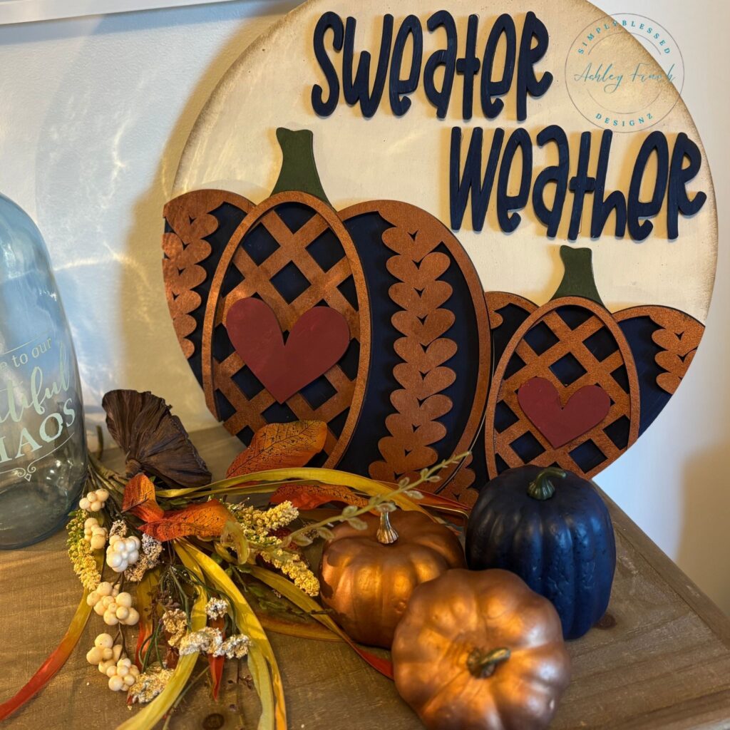 Round wooden fall craft kit sign with pumpkins, hearts, and Sweater Weather lettering